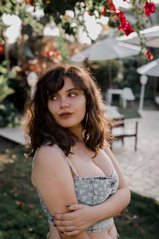 A young woman poses in a lush garden with vibrant flowers, exuding a sense of elegance and tranquility.