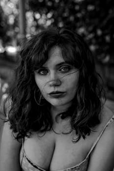 一幅年轻女子的艺术黑白肖像，在户外拍摄，她拥有迷人的眼睛