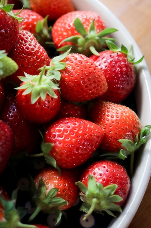 Free Close-up view of freshly picked strawberries in a white bowl showcasing vibrant red color. Stock Photo