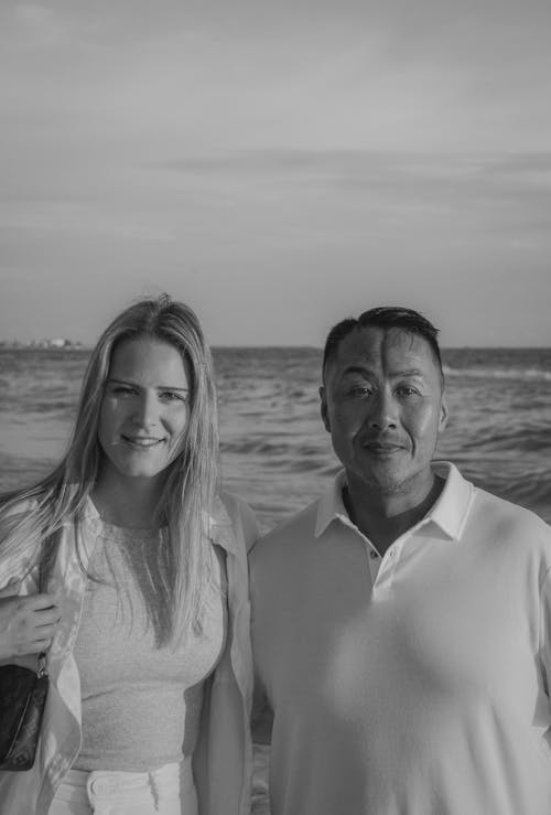 Black and White Photo of a Man and Woman Standing on a Beach 