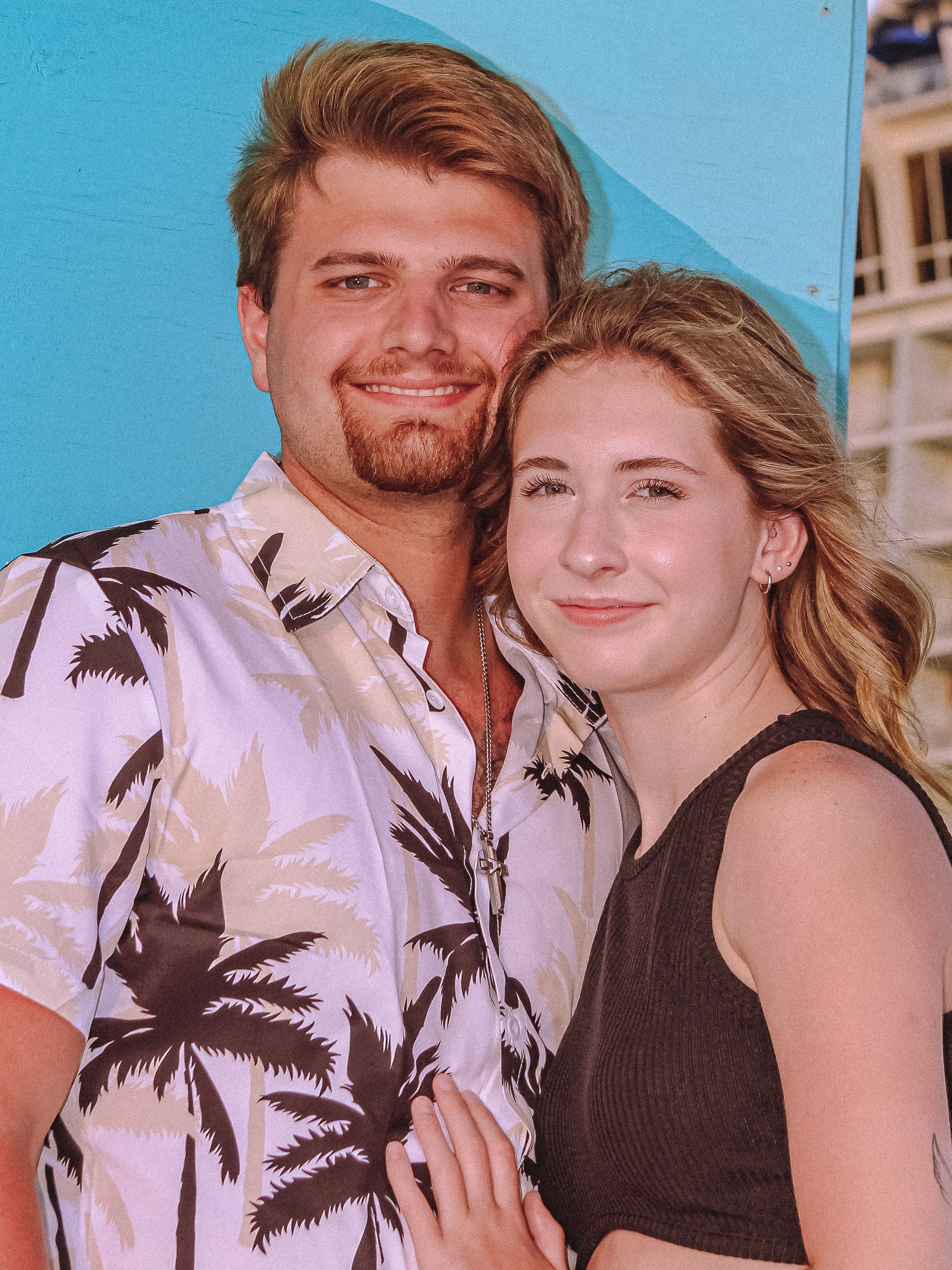 Smiling couple embracing by a blue wall outdoors in St. Petersburg, FL.