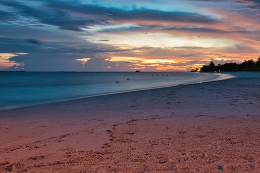 Serene beach sunset over calm seas in Hinnavaru, Maldives. Perfect for travel and relaxation.