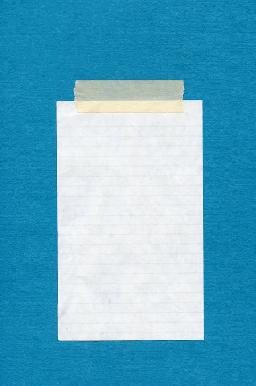 Close-up of a Blank Note Taped to a Blue Wall 