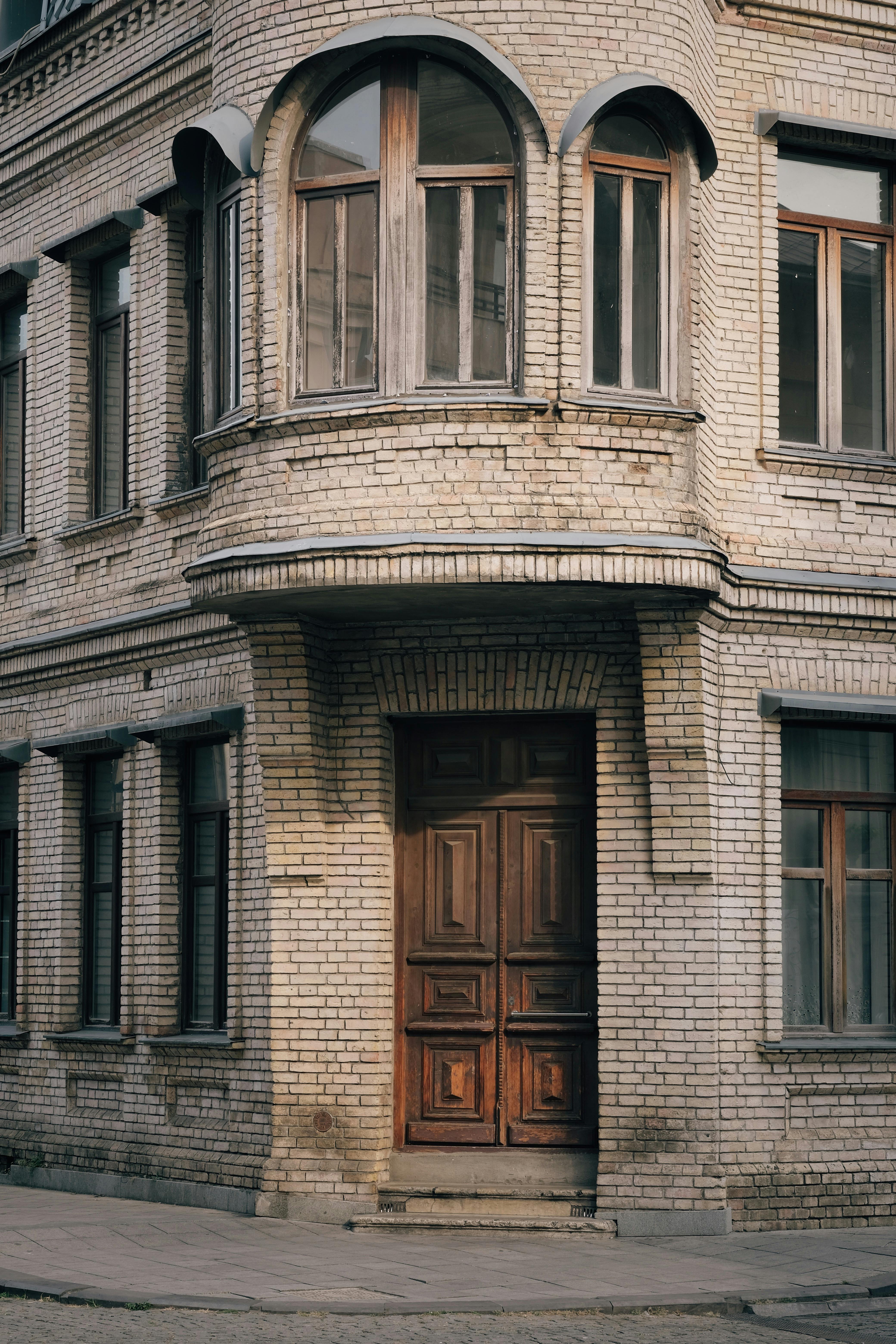 Old urban structure featuring a white brick facade and wooden door, capturing a classic architectural style.