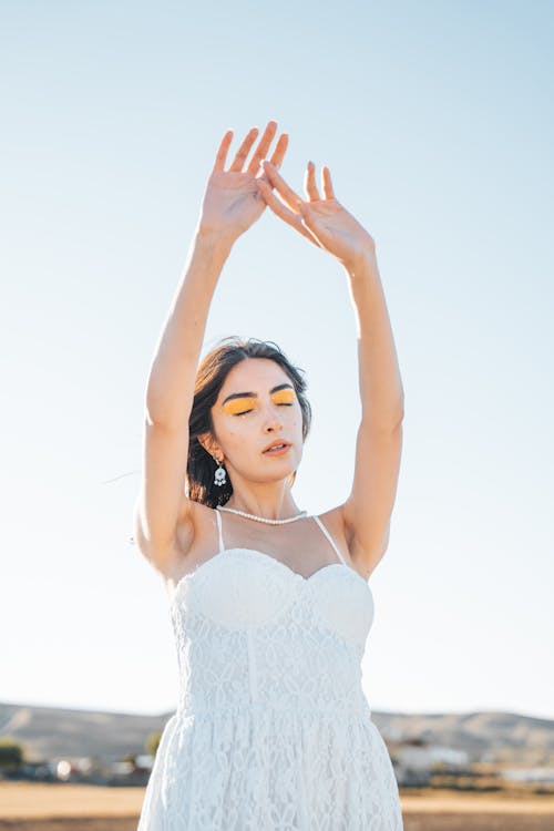 Young Woman in a White Dress Posing Outside in Sunlight 