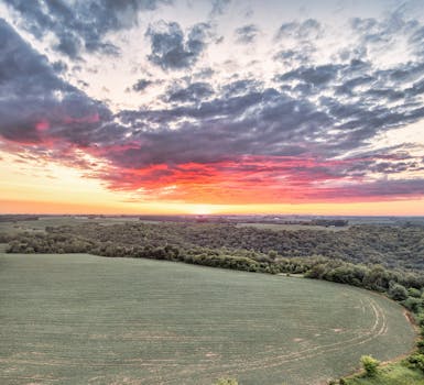 Breathtaking sunrise over a rural field and forest in Pepin, WI with vibrant clouds.