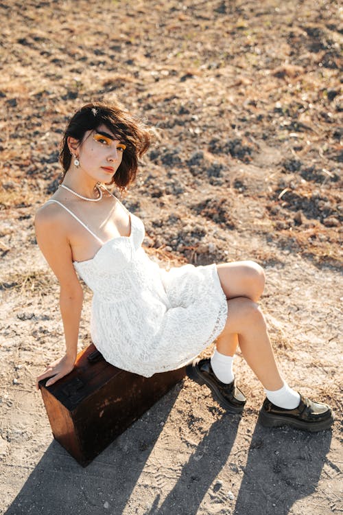 Young Model Sitting on an Old Suitcase Wearing White Spaghetti Strap Mini Dress