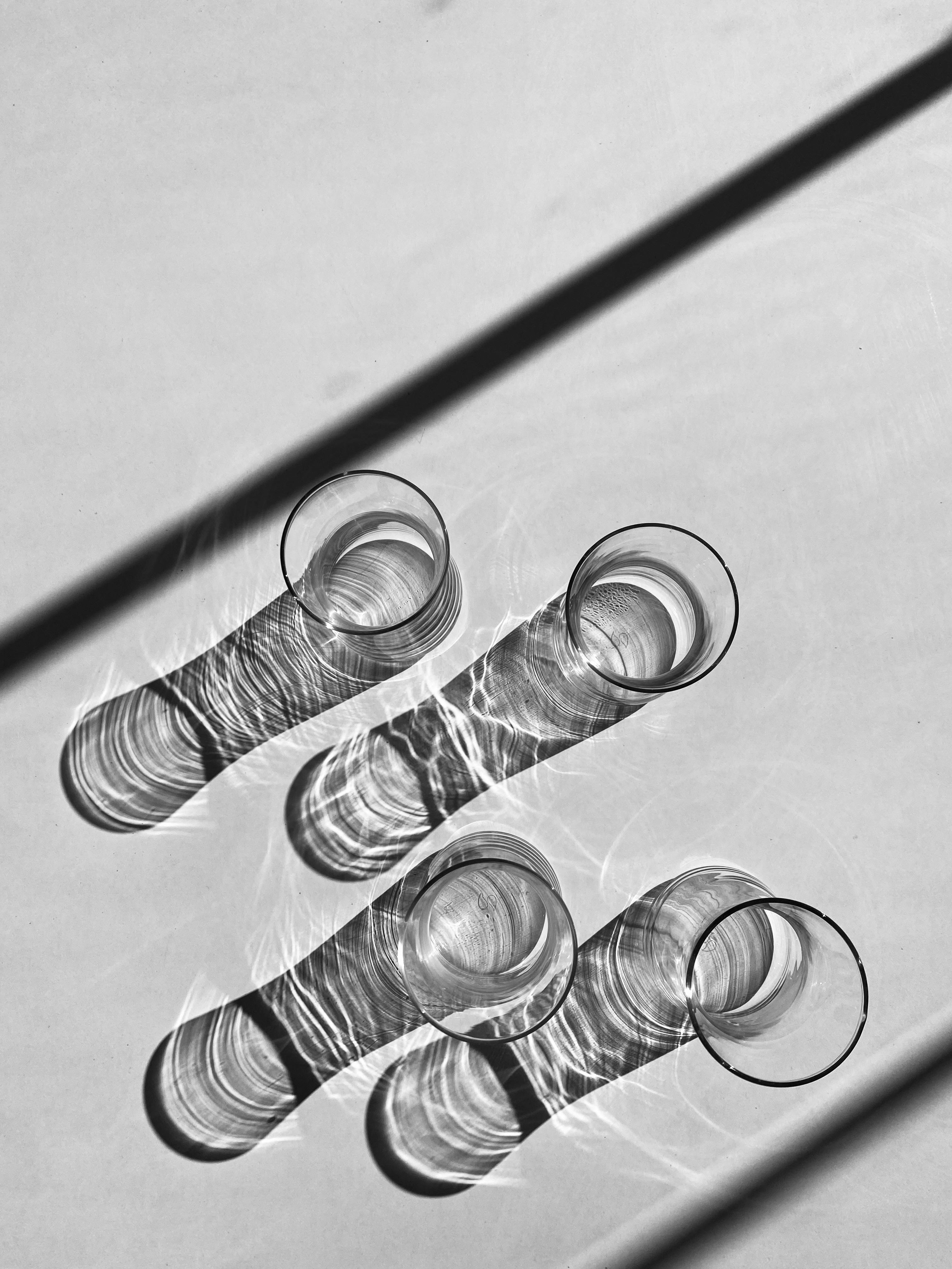 Black and white photo of glasses casting dramatic shadows with light play.