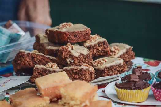 Close-up of homemade brownies with walnuts and assorted cupcakes on a festive table.