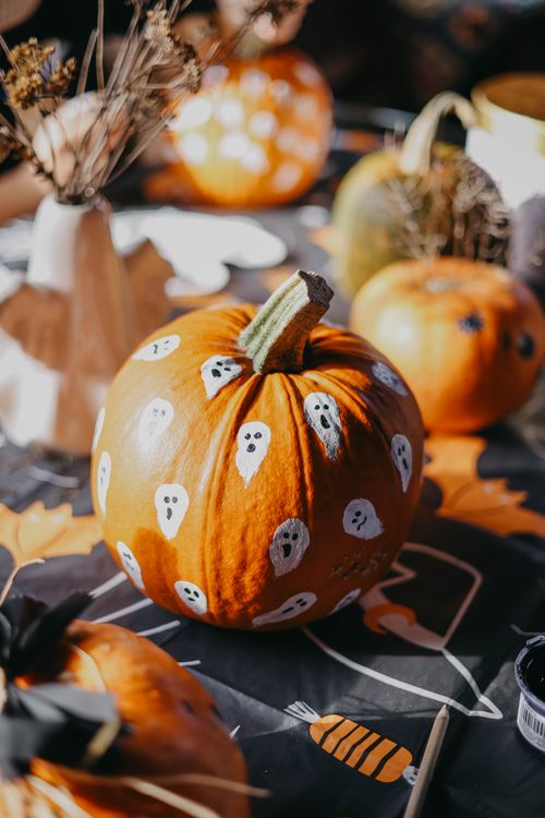 Free Vibrant Halloween pumpkins decorated with white ghost motifs, creating a festive autumn scene. Stock Photo