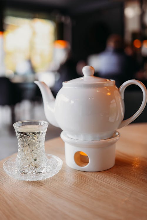 Turkish Tea Glass on Plate and White Teapot on Burning Candle