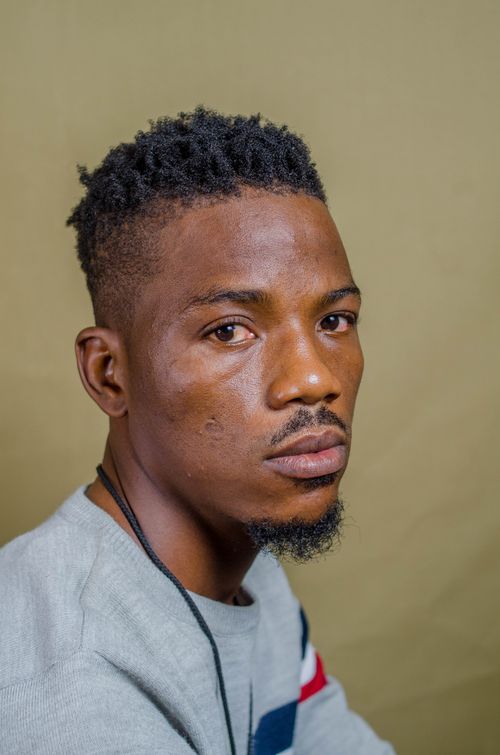 Free Close-up portrait of a young black man with beard and mustache, wearing casual attire. Stock Photo