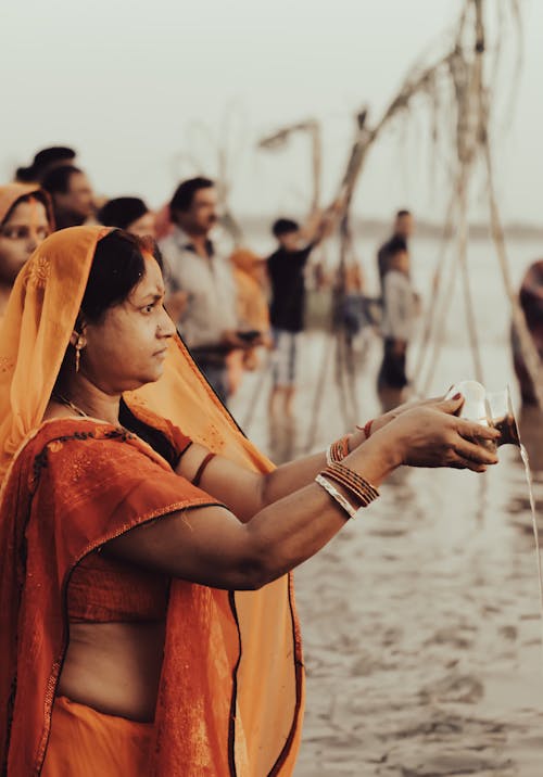 Woman in an Orange Saree and Veil Standing in the Water 