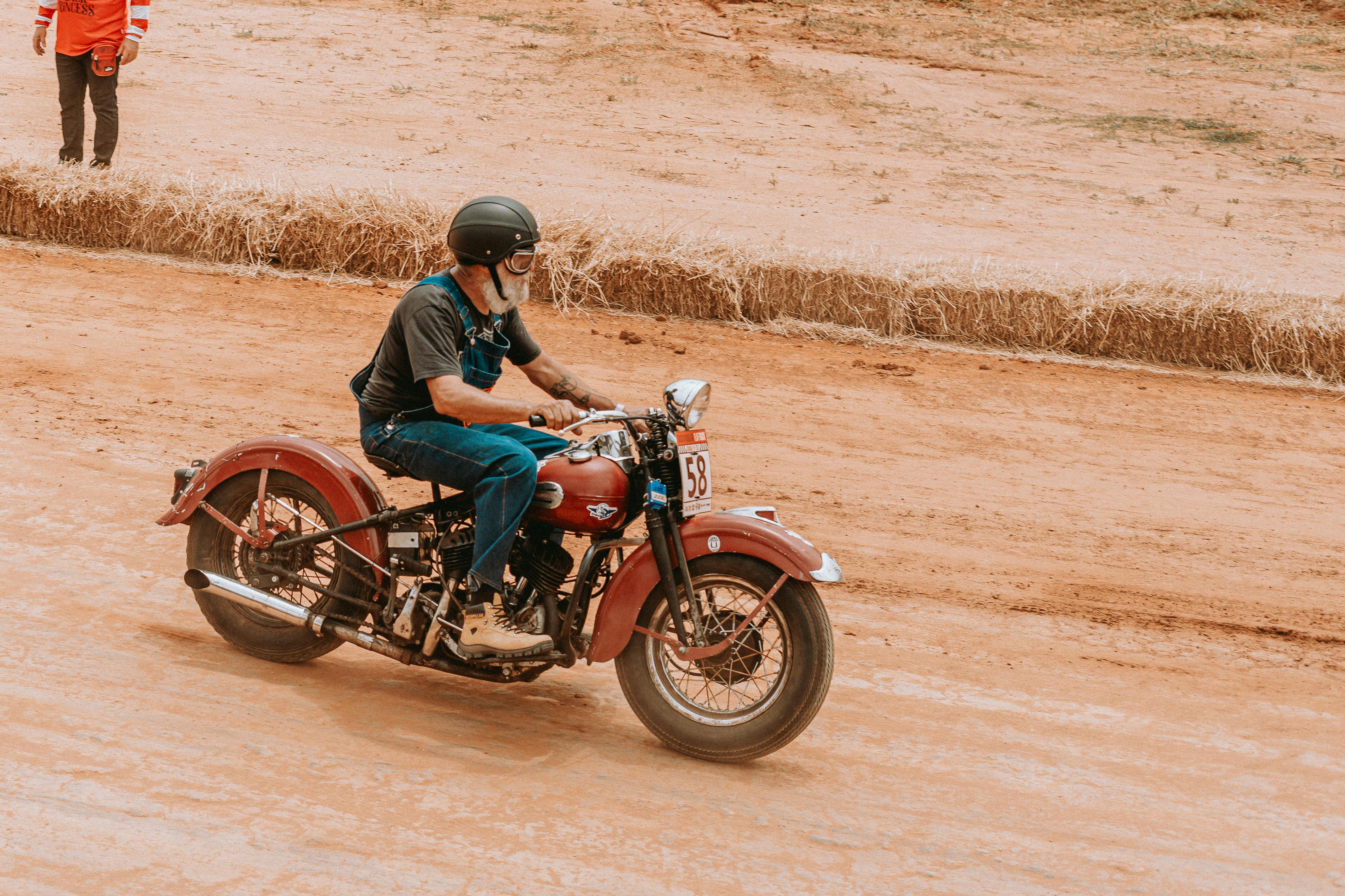 A motorcyclist racing a classic Harley-Davidson on a dirt track, showcasing speed and style.