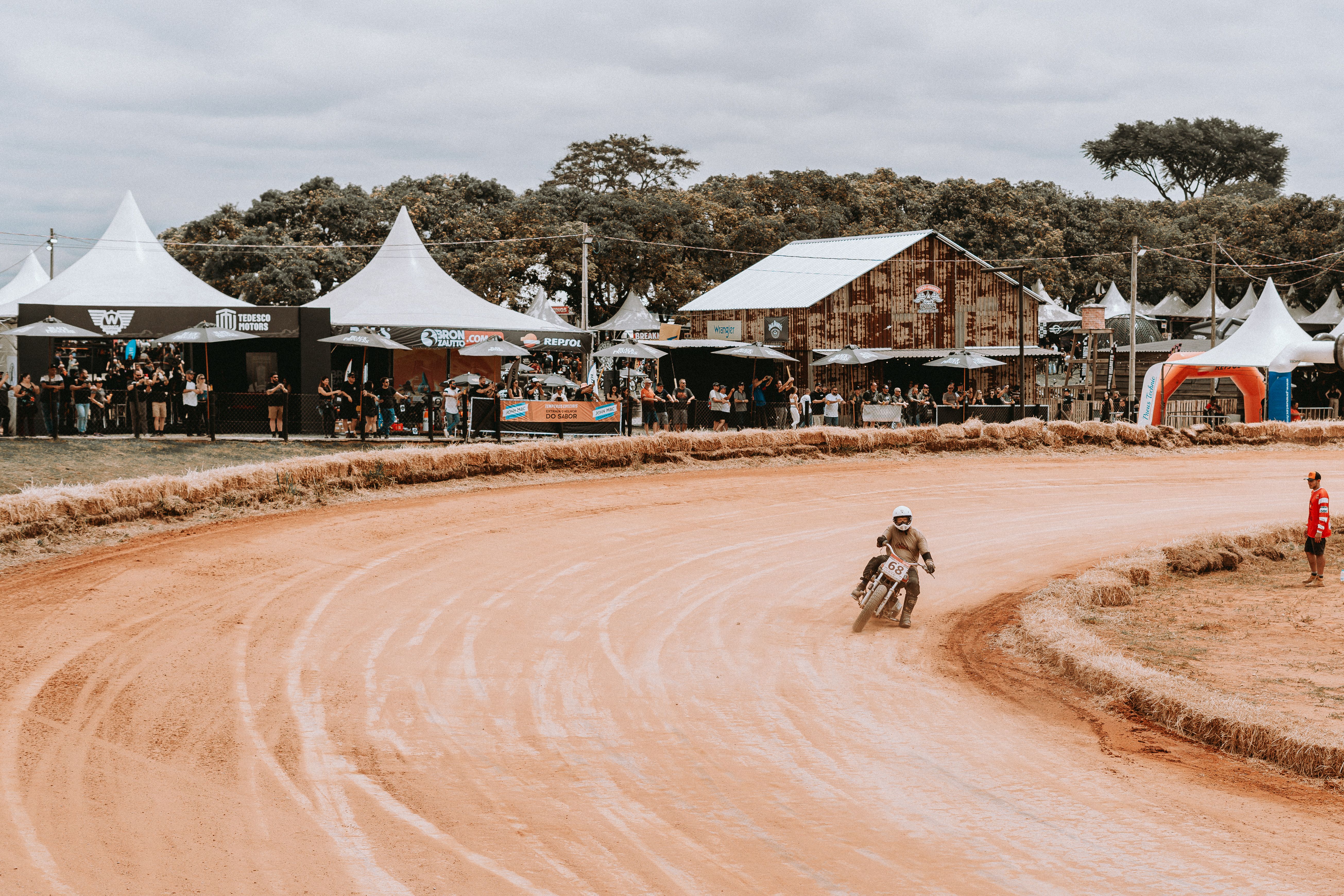 Motorcycle racer speeding on a dirt track during an outdoor event with spectators.