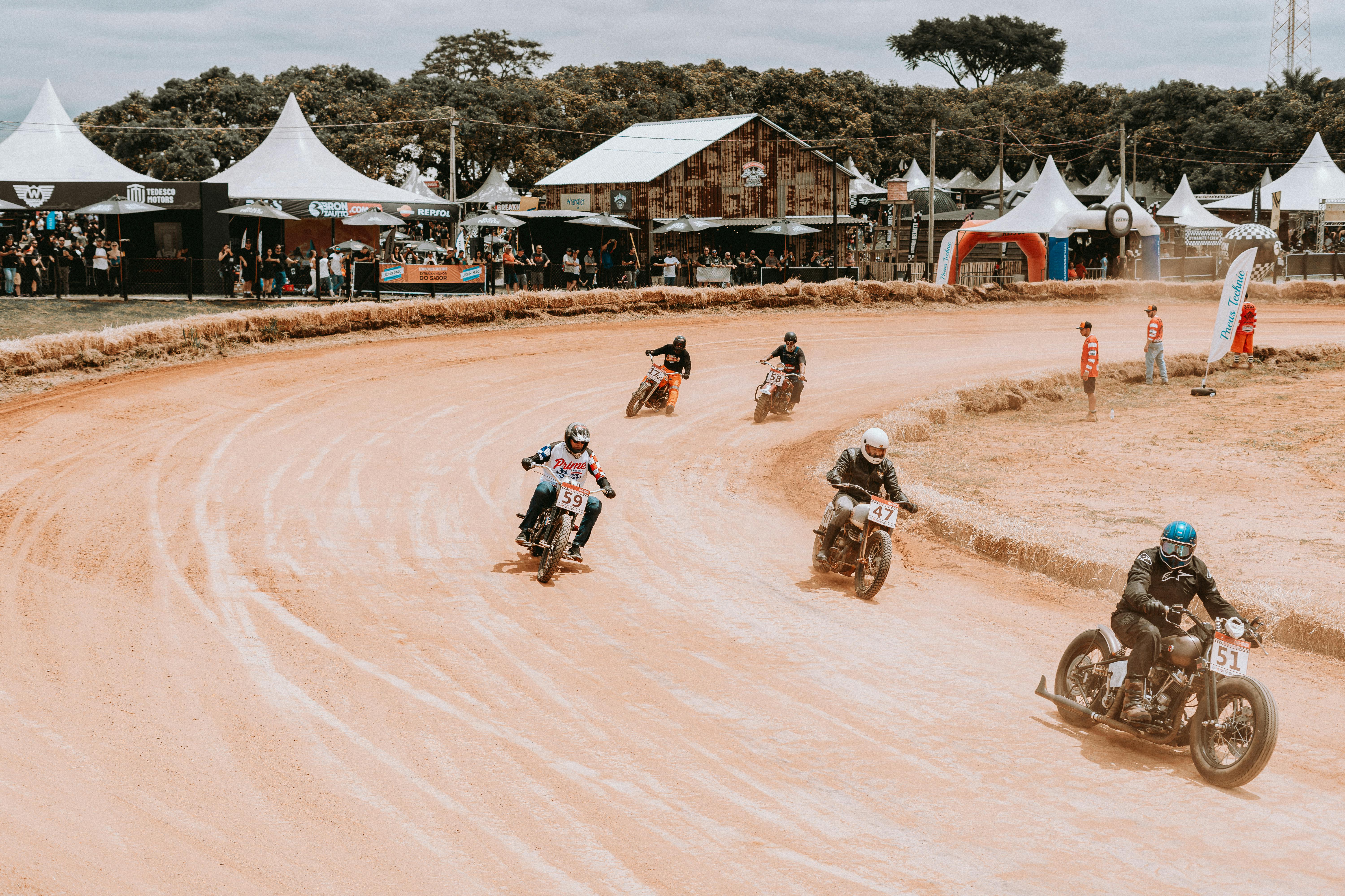 Motorcycle racers competing on a winding dirt track at an outdoor event.