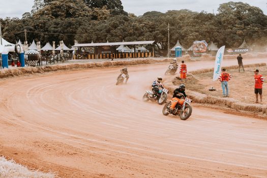 Motorcyclists racing on a dirt track at an outdoor sports event surrounded by spectators.