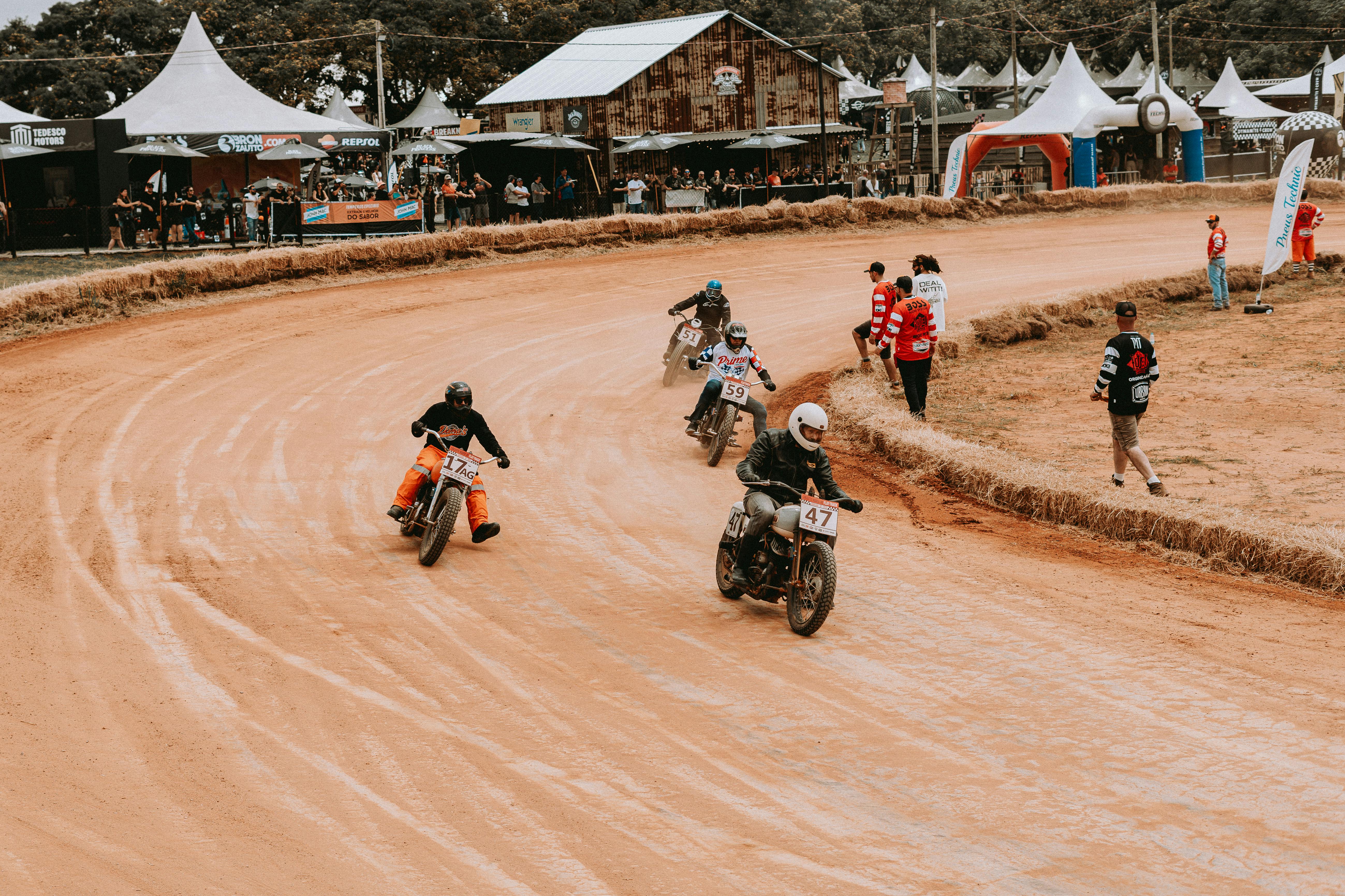 Motorcycles racing on a dirt track with spectators, capturing speed and excitement.