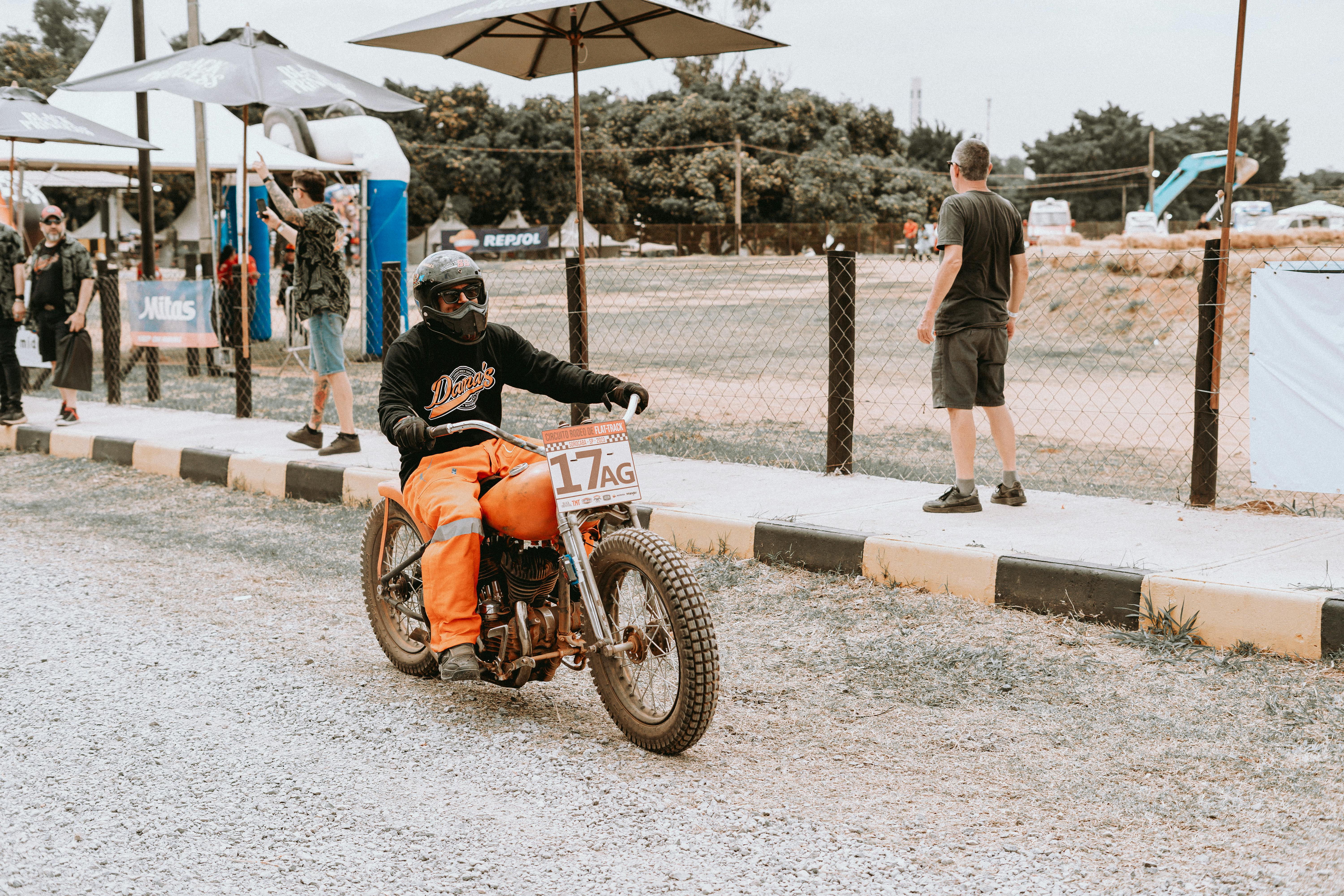 Motorcyclist riding a vintage Harley-Davidson during an outdoor race event on a sunny day.