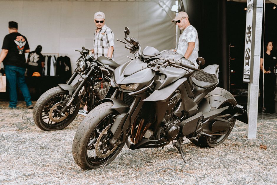Close-up of sleek motorcycles with people at an outdoor motorcycle event.