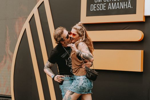 A joyful couple with tattoos laughing and interacting playfully outdoors.