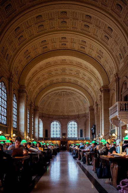 Ornate reading room in Boston Public Library with classical architecture and vaulted ceiling.