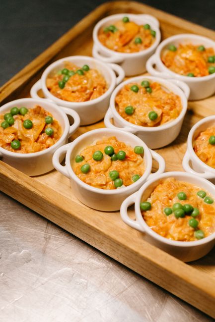 A golden, puffed sausage and cheddar breakfast casserole in a white baking dish, sliced into squares and topped with sliced green onions, steam rising from a corner piece on a plate.