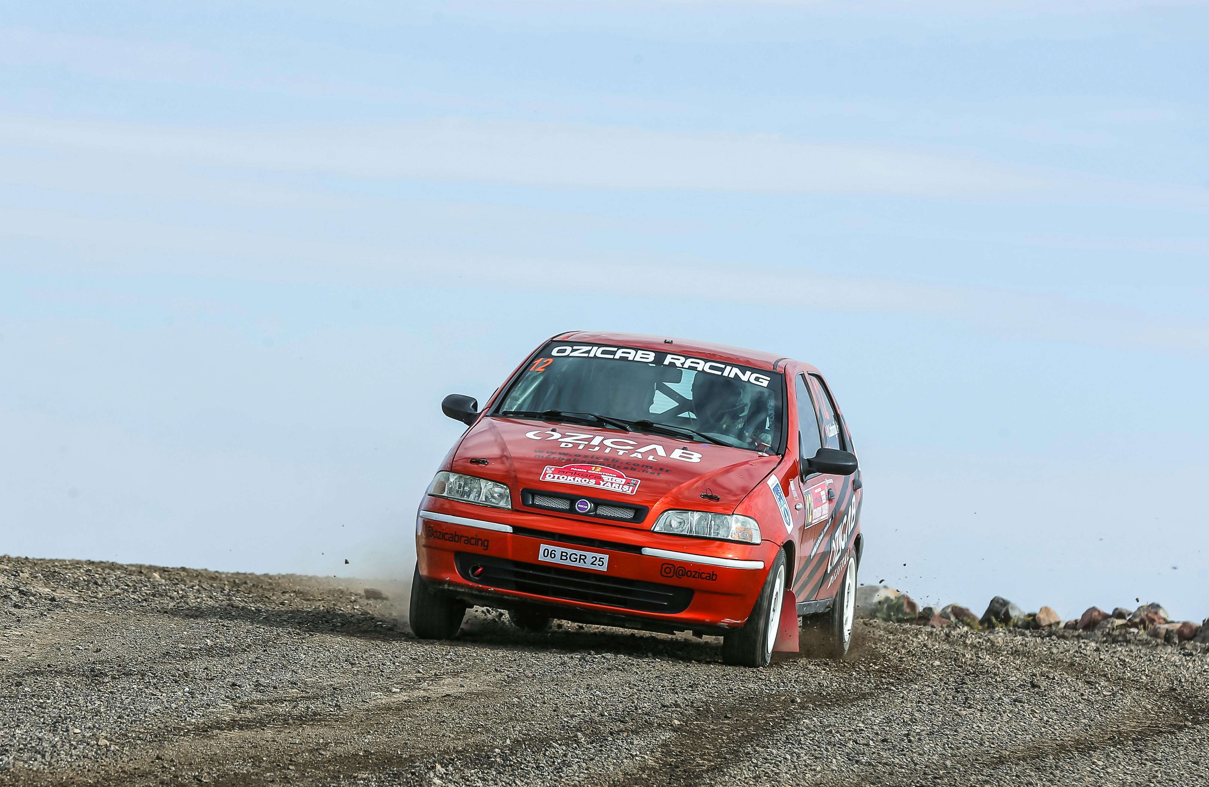a red car driving on a dirt road