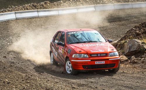 Free A red Fiat car races on a dusty rally track, showcasing speed and agility. Stock Photo