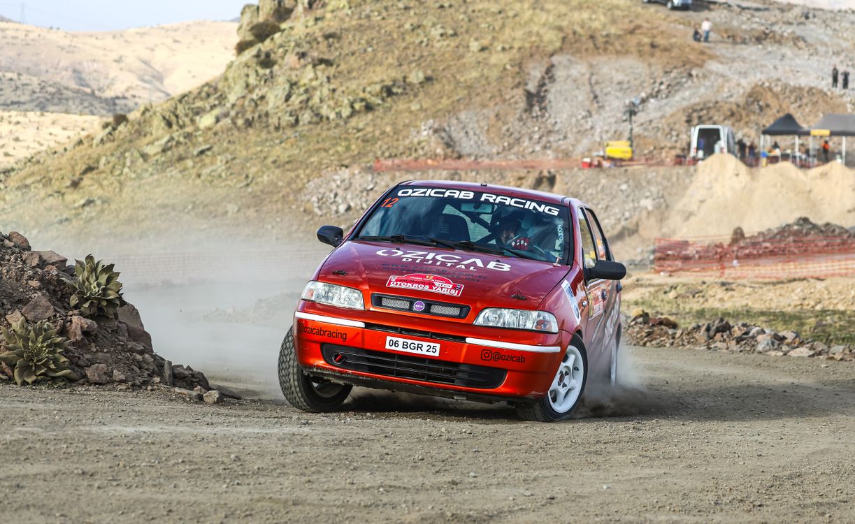 A red car is driving on a dirt road · Free Stock Photo