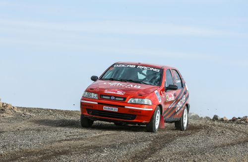 Free A red Fiat Palio rally car in action on a gravel track during a daytime race. Stock Photo