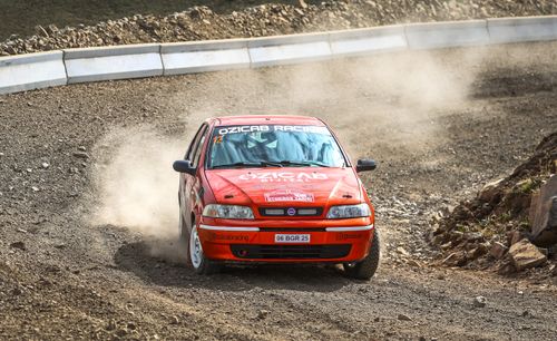 Free Fiat Palio car speeding through a dusty gravel rally track with skillful maneuvering. Stock Photo