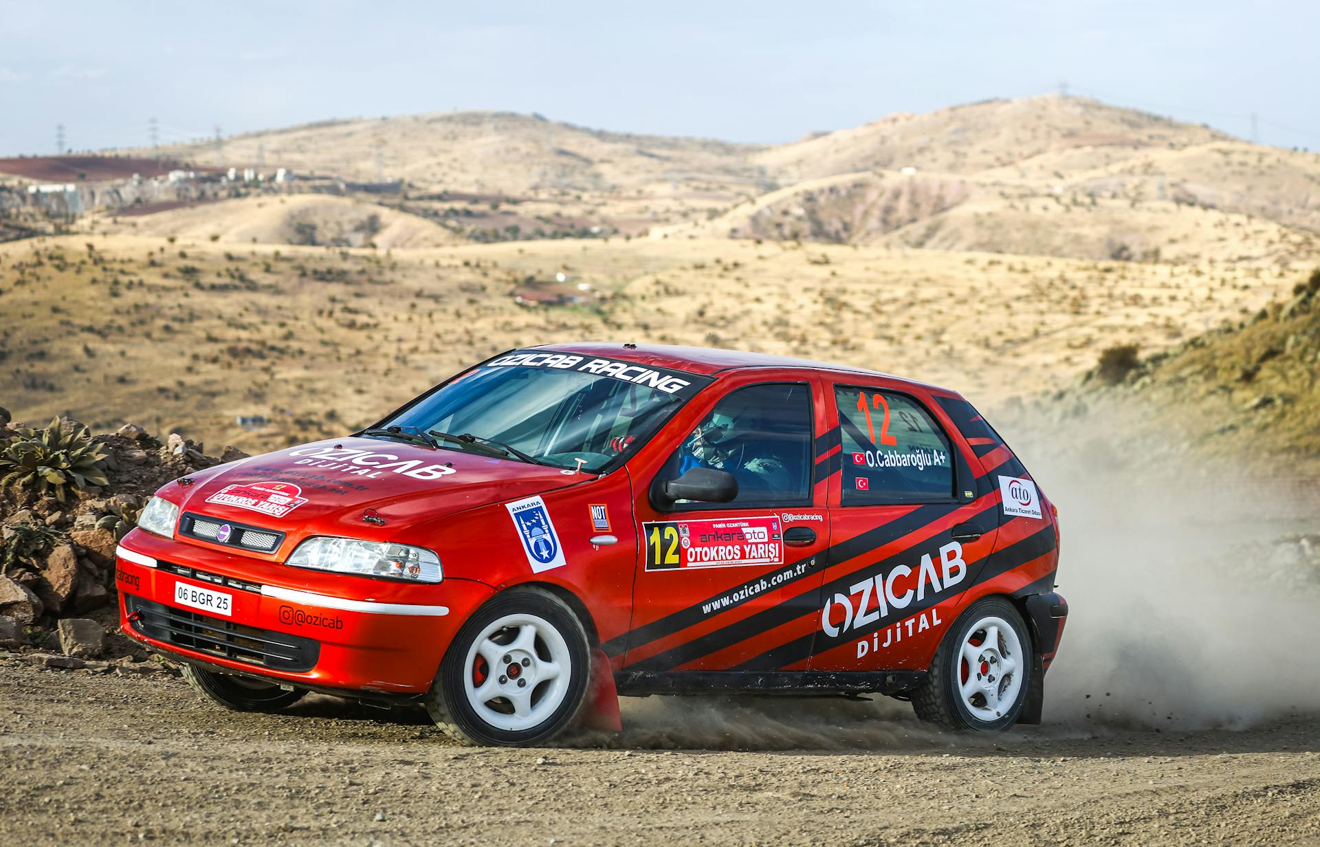 Red Fiat Palio racing through a dusty track in Ankara, Türkiye, showcasing rallycross action.