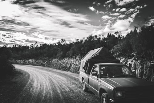 Black and White Photo of a Truck Riding on a Road in the Countryside 