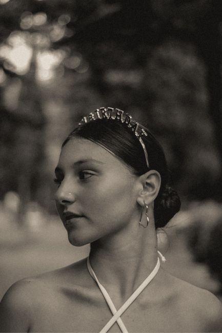 Artistic black and white portrait of a woman wearing a tiara outdoors.