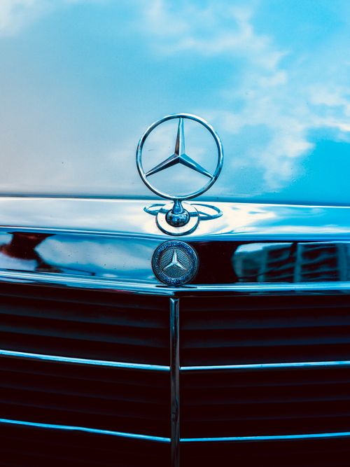 Free Vertical shot of a Mercedes-Benz grille with logo against a blue sky reflection. Stock Photo