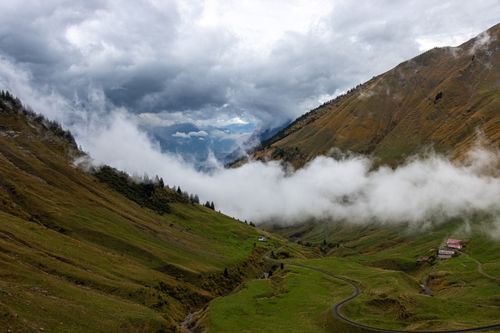 Free Dramatic view of a lush green valley surrounded by mountains and low clouds. Stock Photo