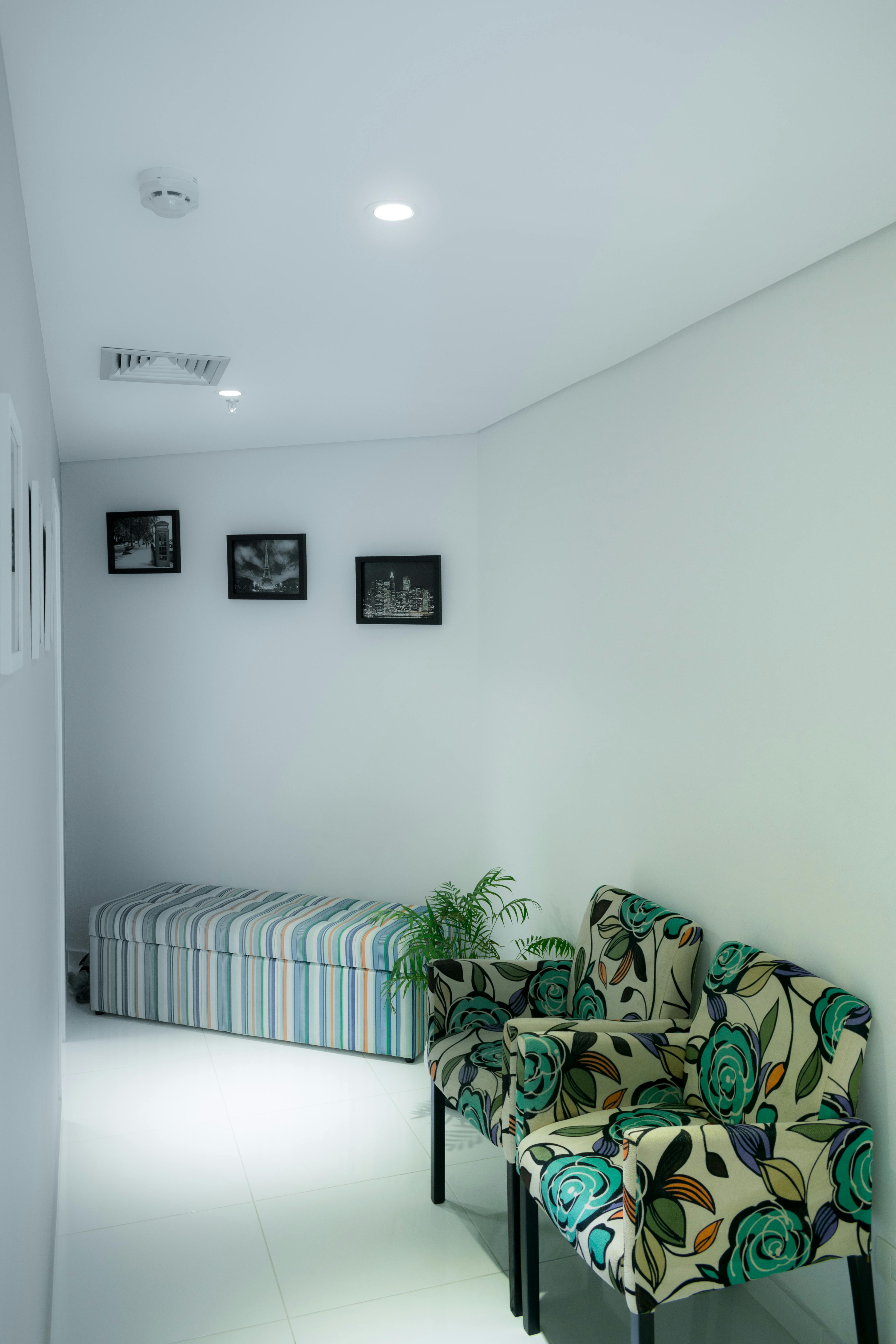 Two White And Green Floral Padded Sofa Chairs Next To Wall