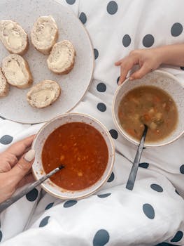 A cozy meal setting with two types of soup and buttered bread slices, perfect for a comforting day.