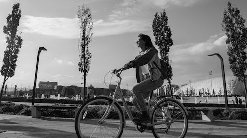 Black and White Photo of a Woman Riding on a Bicycle in a City