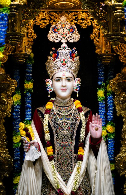 Free Colorful depiction of a Hindu deity in traditional temple setting with elaborate carvings and floral garlands. Stock Photo