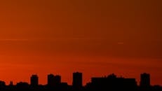 摩天大楼的剪影映衬着城市景观中充满活力的日落天空