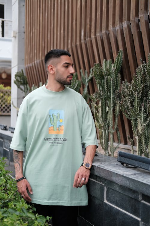 Model in a Green T-shirt With a Print Next to Cacti in the Garden