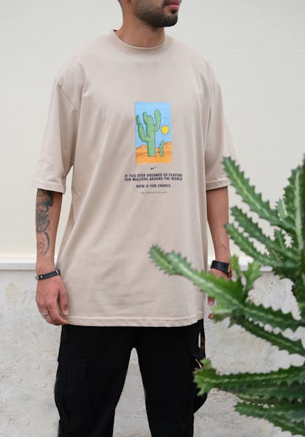 Model in a Beige Nike T-shirt with a Print Next to a Cactus · Free ...