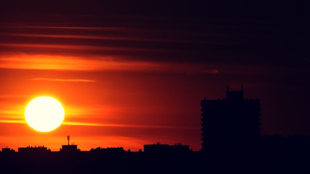 Silhouette of skyscrapers against a vibrant sunset in the city skyline.