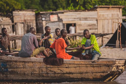 Free A group of men socializing and fishing on a wooden boat by the shore. Stock Photo