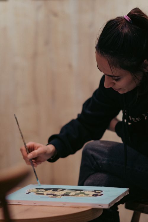 Free Focused woman painting with a brush on a canvas in an indoor setting. Stock Photo