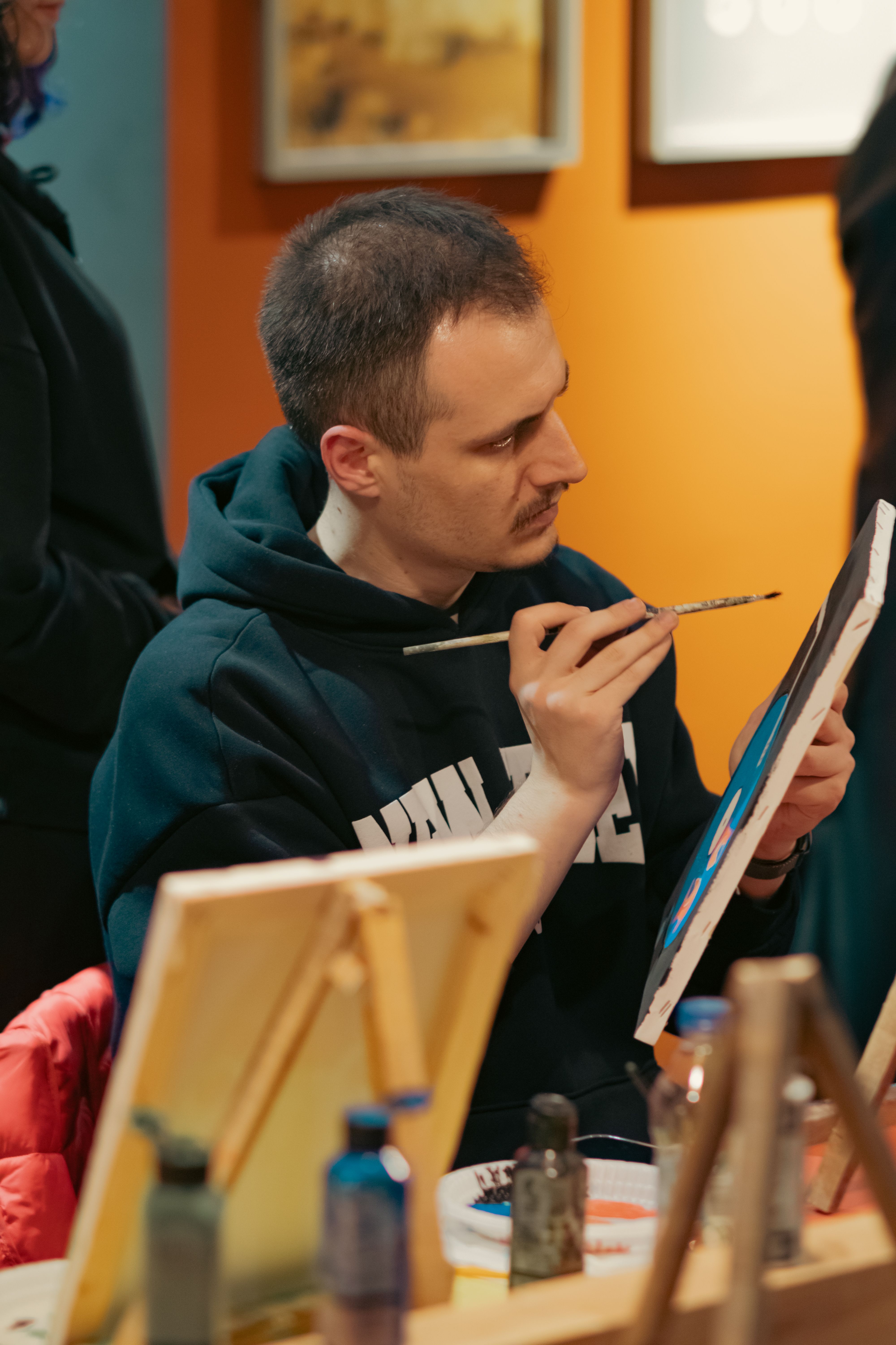 Adult male painting on canvas in a creative arts studio. The setting features a warm and artistic atmosphere.