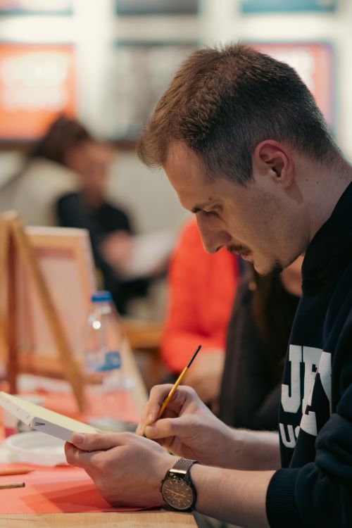 Free Young man concentrating on his artwork at an art class, holding a paintbrush. Stock Photo