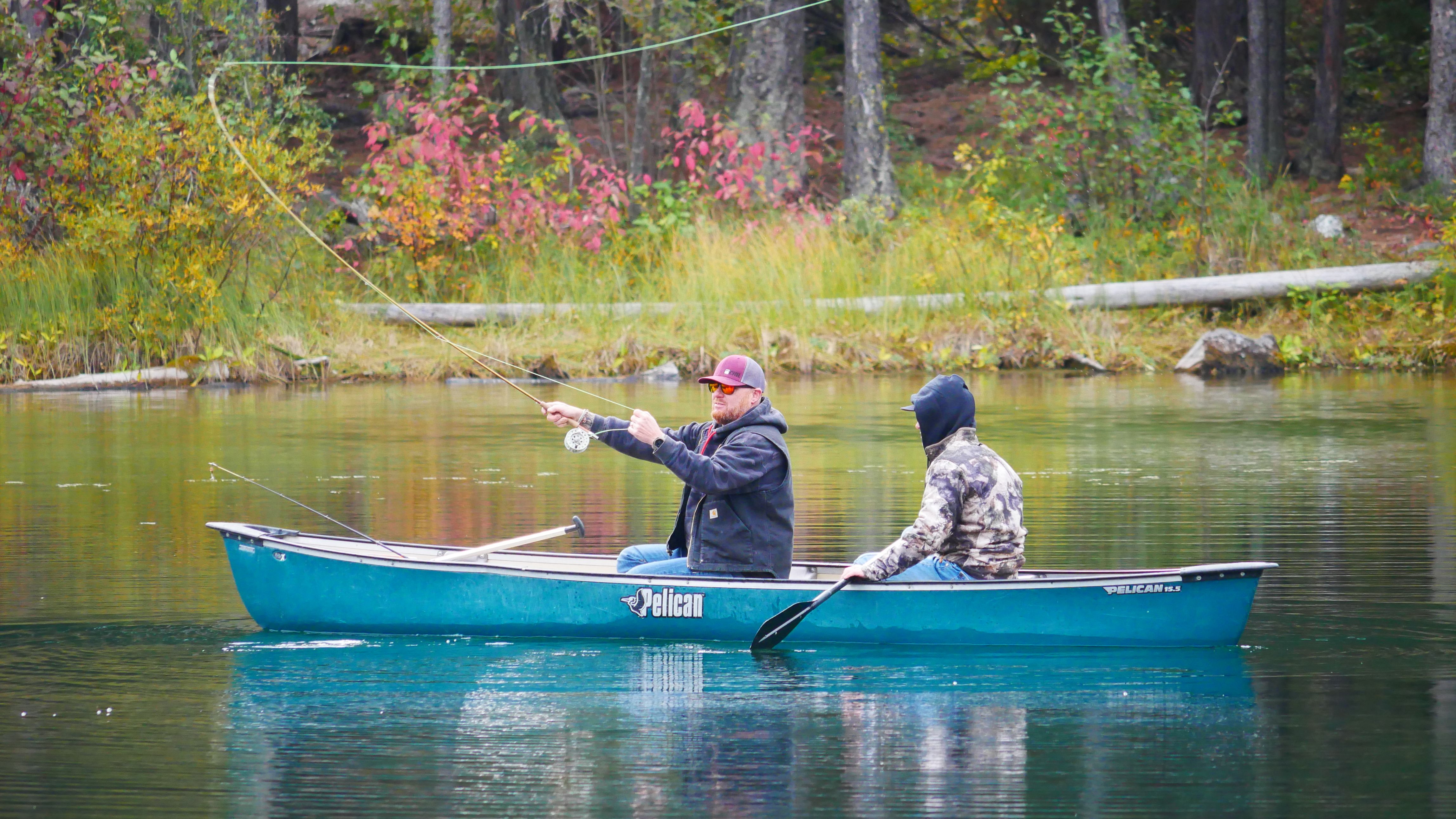 Two men fishing from a canoe at a picturesque lake in Canal Flats, BC.